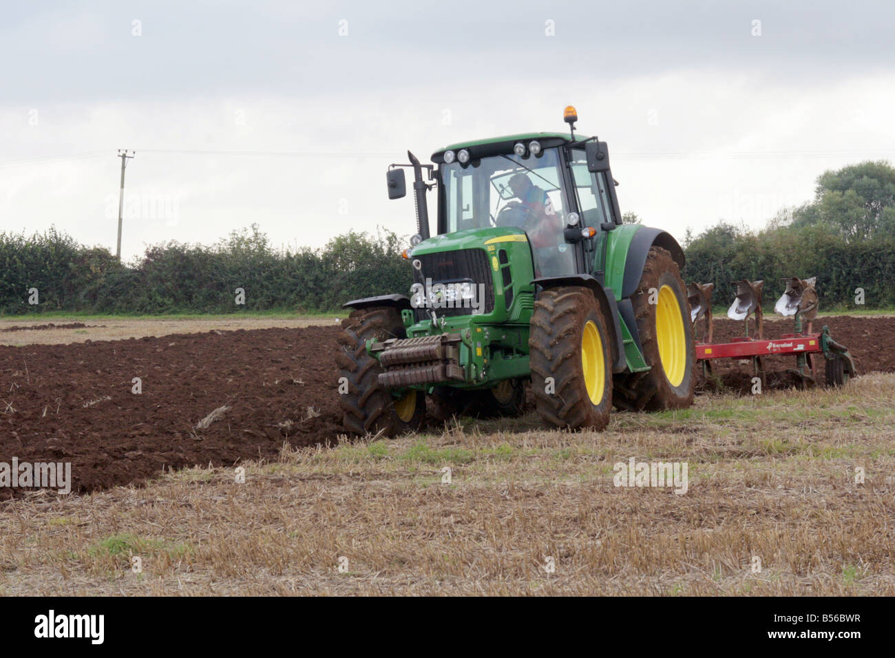 Ein Bauer bei der Arbeit, einen John Deer Traktor seine Felder pflügen zu fahren Stockfoto