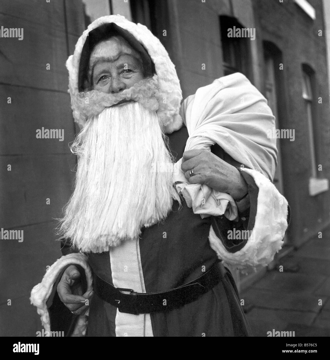 Eine ältere Frau als Weihnachtsmann verkleidet auf ihrem Weg zum Engagement von Nachbarskinder begleitet. Dezember 1969 Z11977-002 Stockfoto