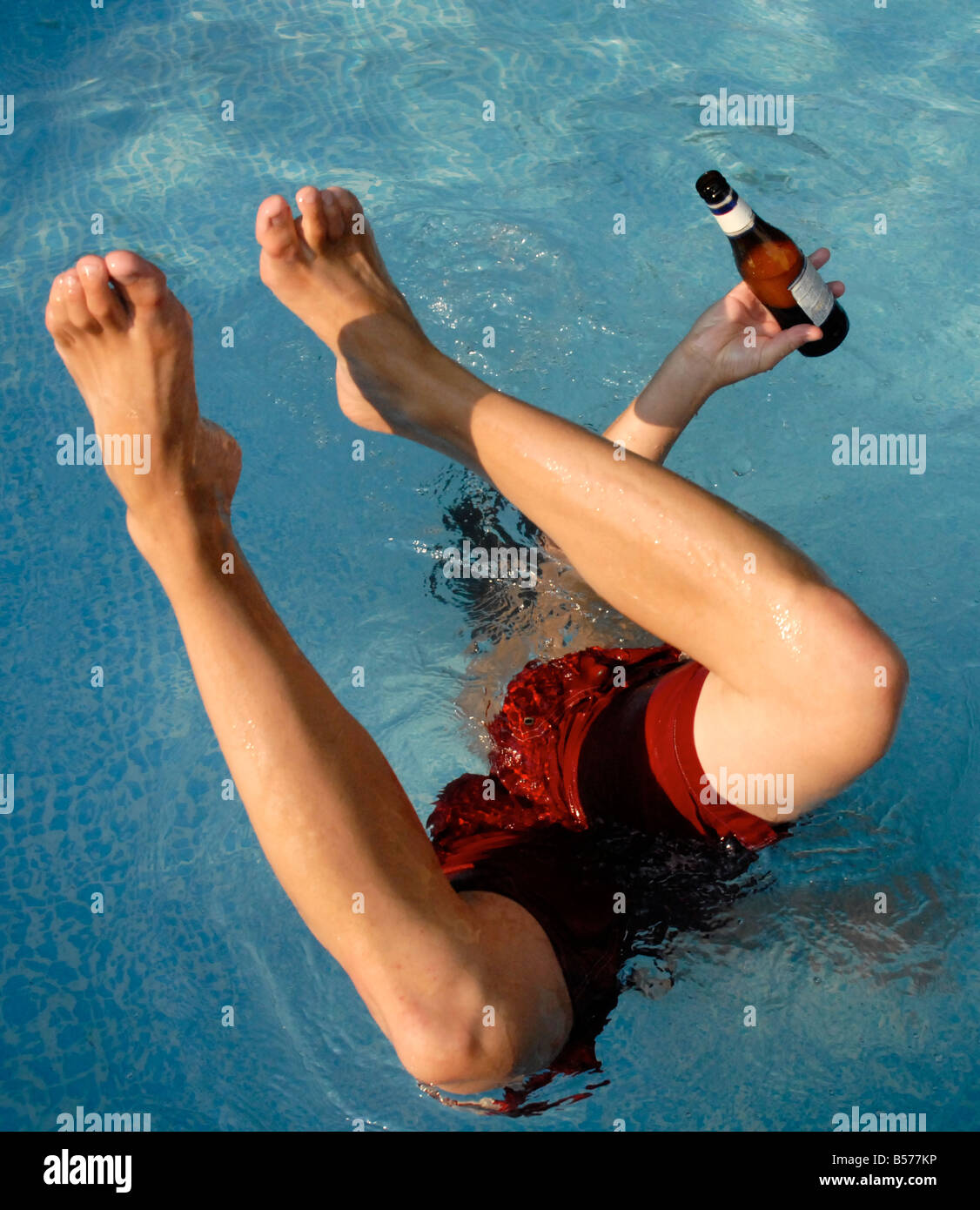 Junger Mann versucht einen einhändige Handstand in einem Pool mit gedrückter sein Bier. Spring Break, Spaß in der Sonne fühlen. Stockfoto