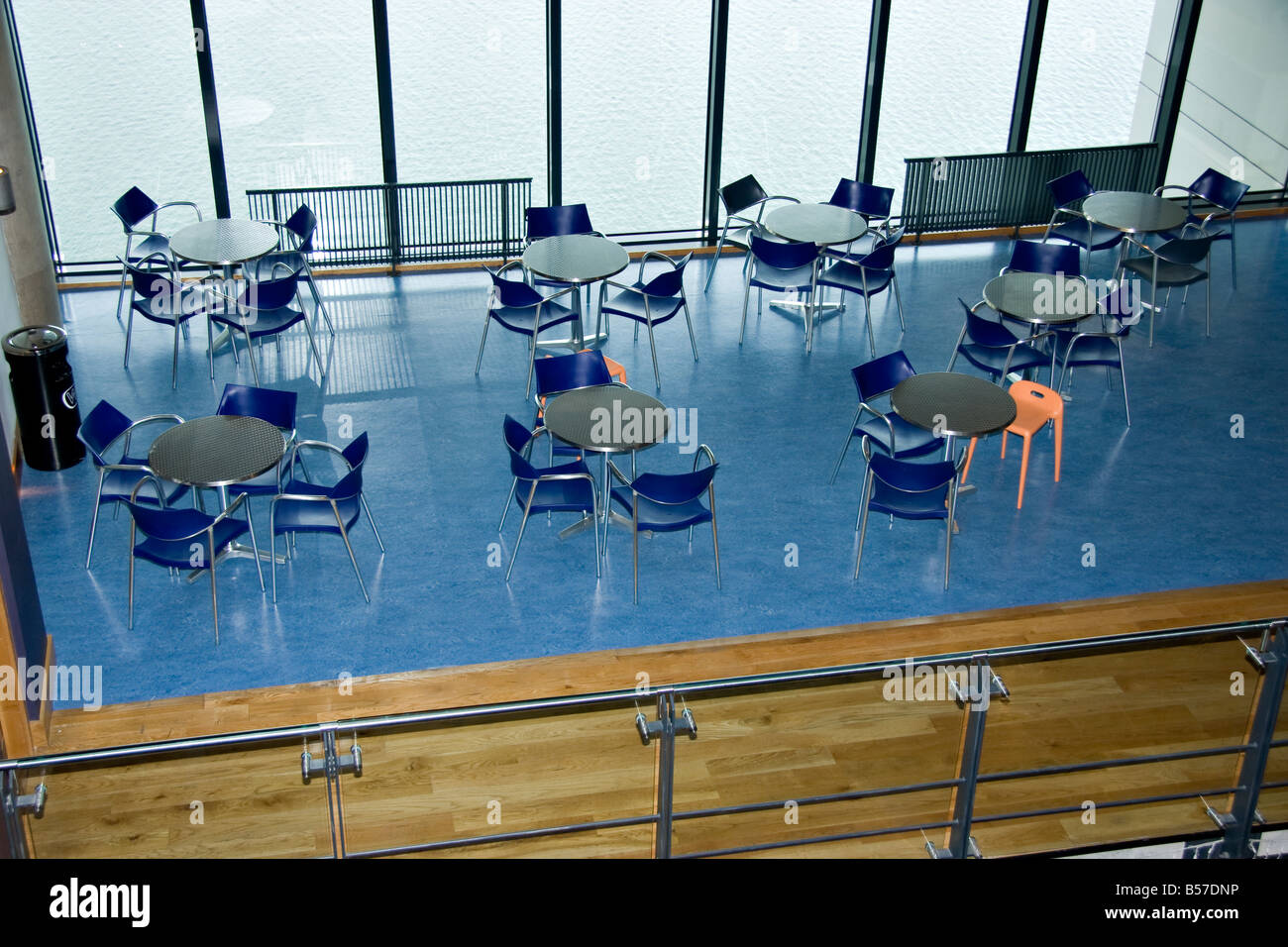 8 kleine Runde Tische und 28 Stühle durch einen verglasten Teil der Wand blicken auf Wasser Stockfoto