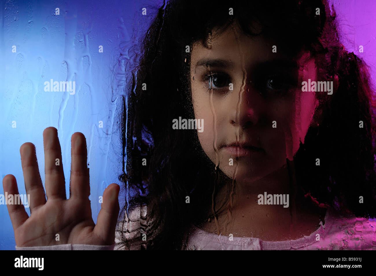 Kind hinter Fenster bei Regen Stockfoto