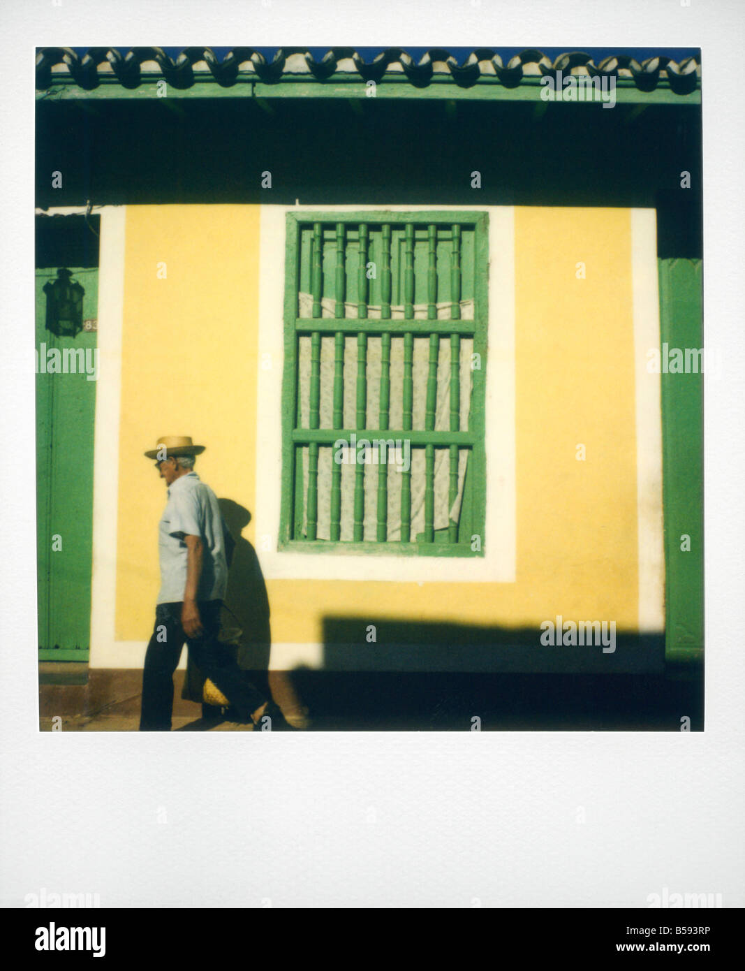 Polaroid von Mann zu Fuß vorbei an gelben Wand mit bemalten grünes Fenster Gitter Trinidad Kuba West Indies Mittelamerika Stockfoto