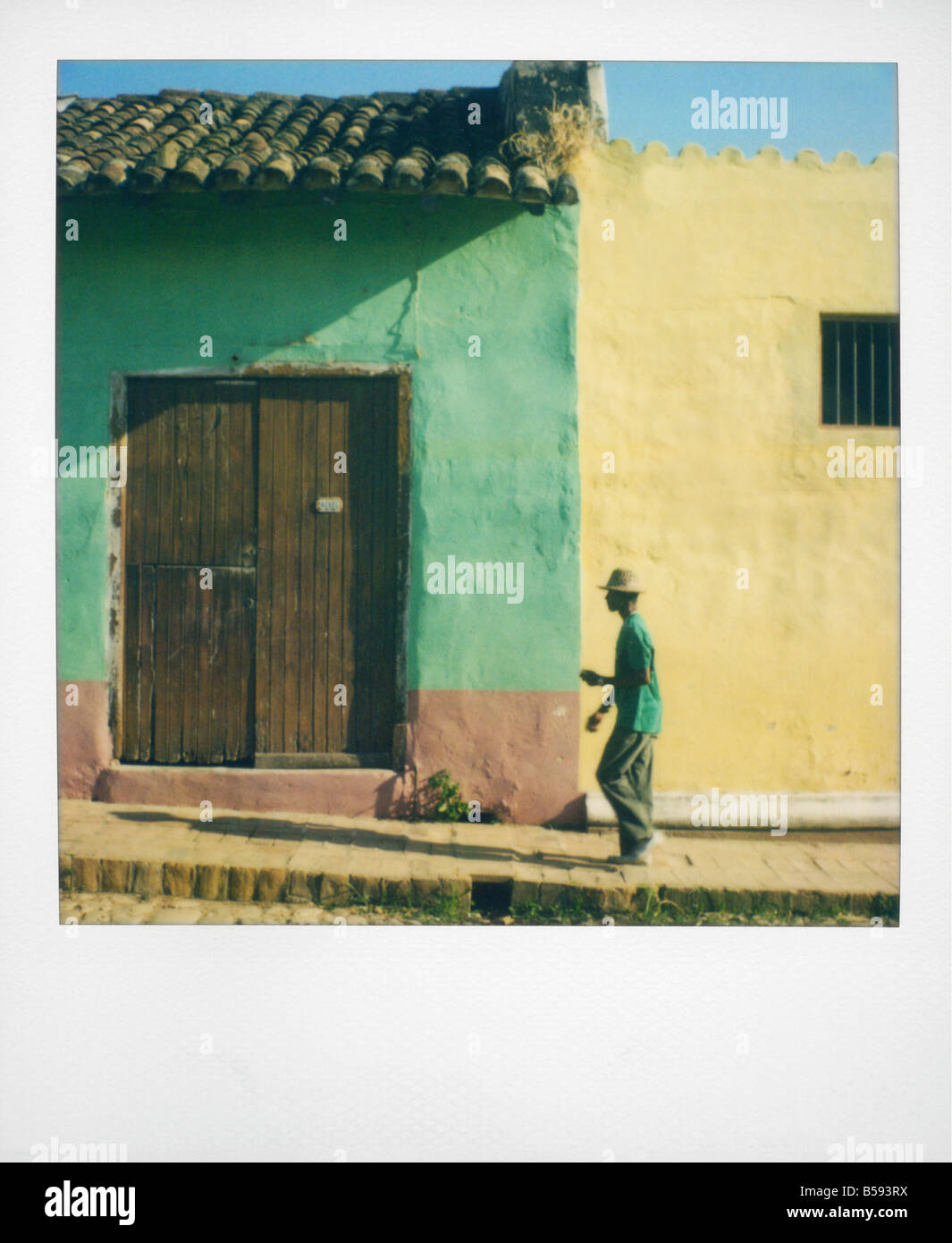 Polaroid von Mann zu Fuß entlang der Straße gegen Häuser gemalt grüne und gelbe Trinidad Kuba West Indies Mittelamerika Stockfoto