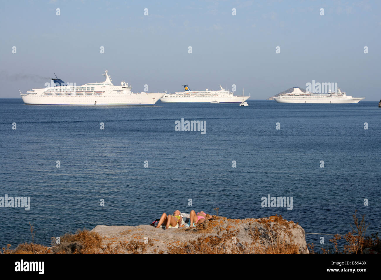 Touristen und drei Kreuzfahrtschiffe in tiefblau auf Patmos Insel Griechenland Stockfoto