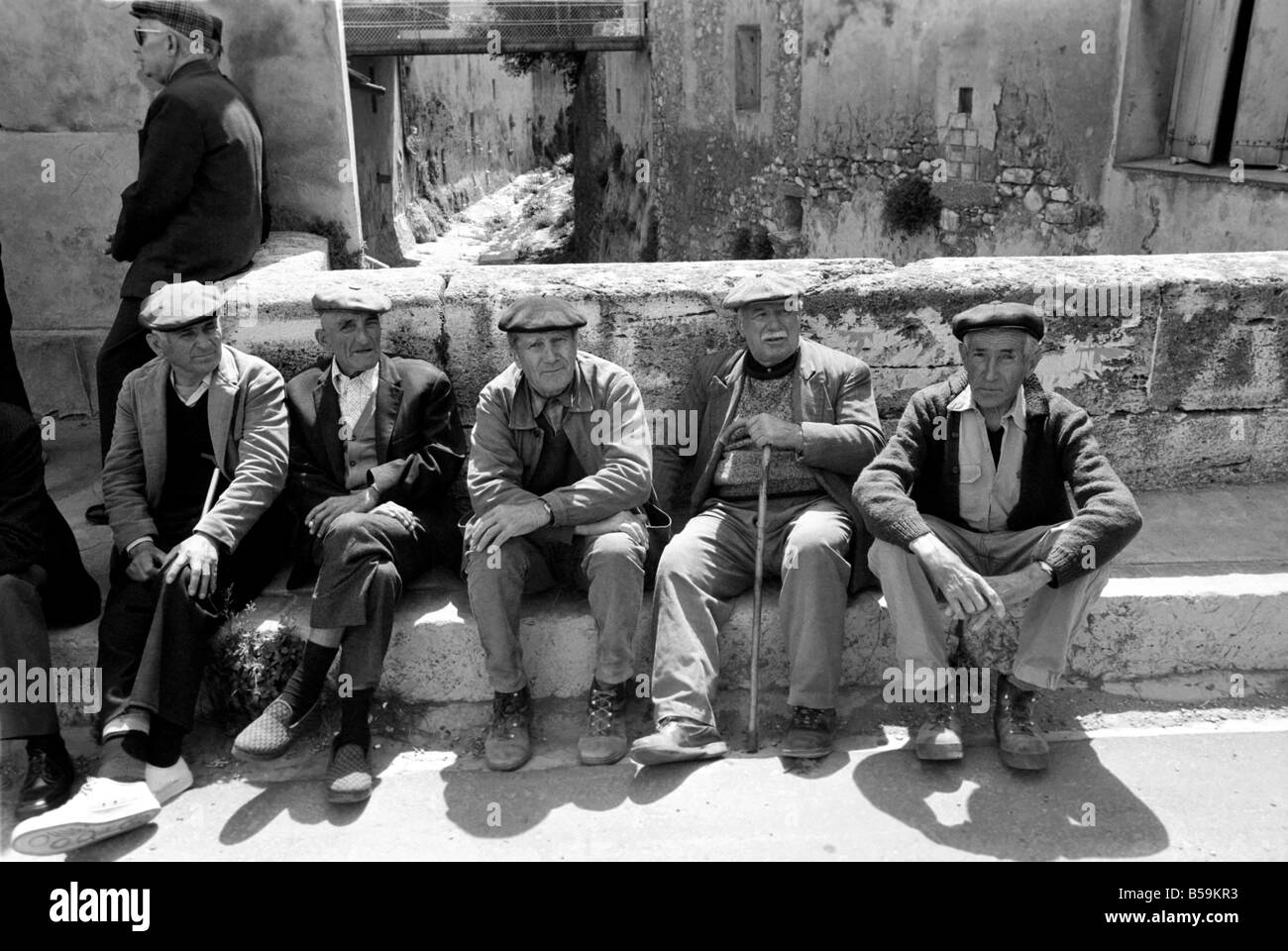 Eine Gruppe von Rentnern sitzen gegen eine Wand in einer Straße in einem französischen Dorf &#13; &#10; April 1975 &#13; &#10; 75-2098a-005 Stockfoto