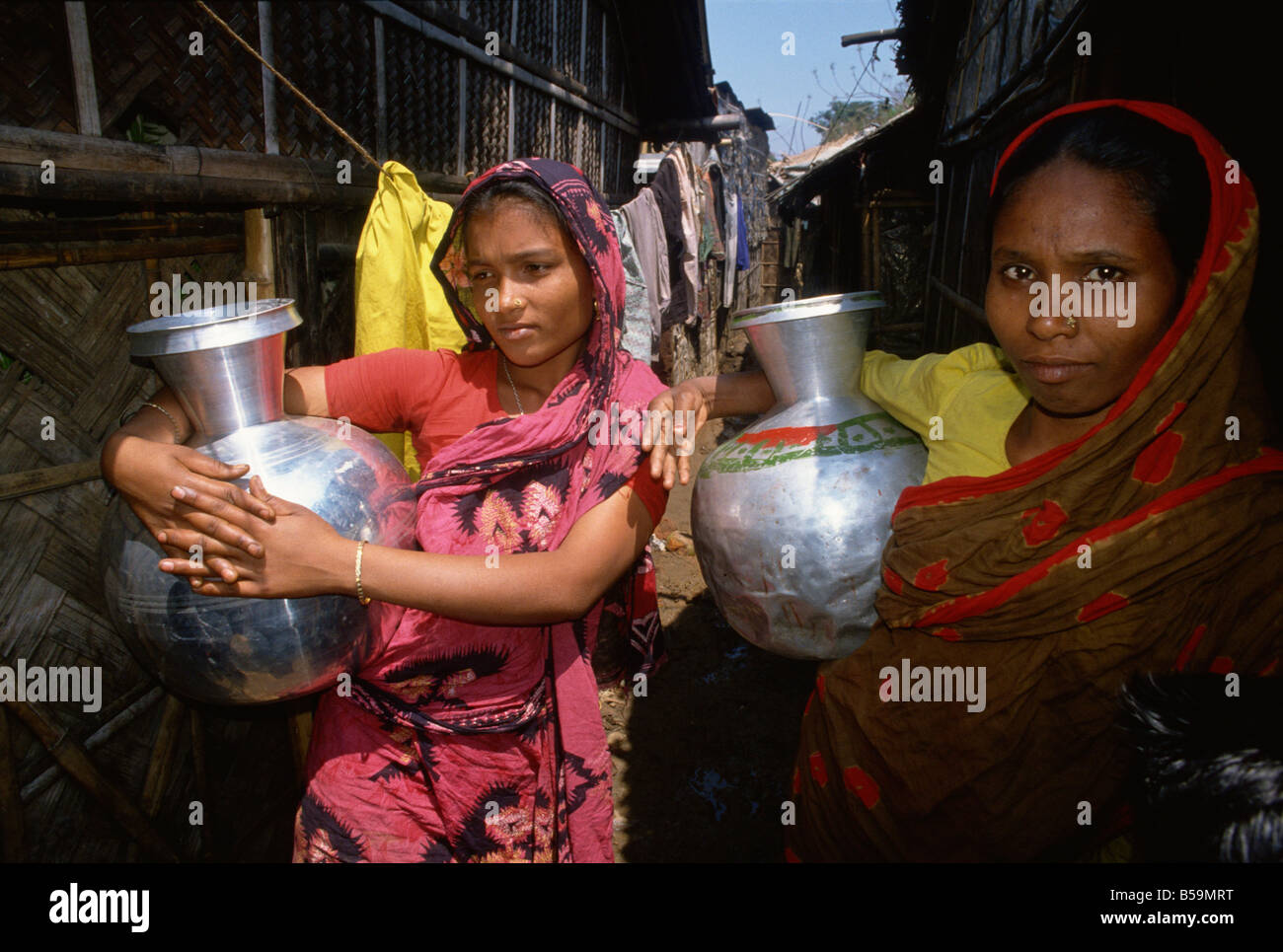 Frauen mit Wasser Töpfe in den Slums, Dhaka, Bangladesch Stockfoto