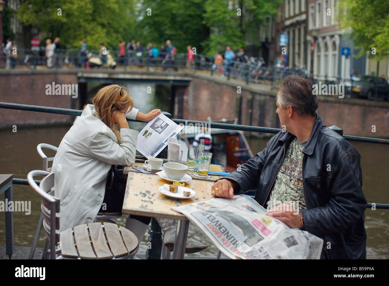 Ein paar ruht eine Amsterdam-Kanal entlang, ihre Zeitung lesen und Kaffee trinken. Stockfoto
