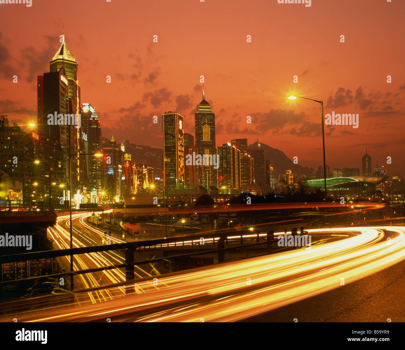 Lichter auf Wolkenkratzer und Verkehr Trails im financial District von Hong Kong bei Sonnenuntergang China Asia Stockfoto