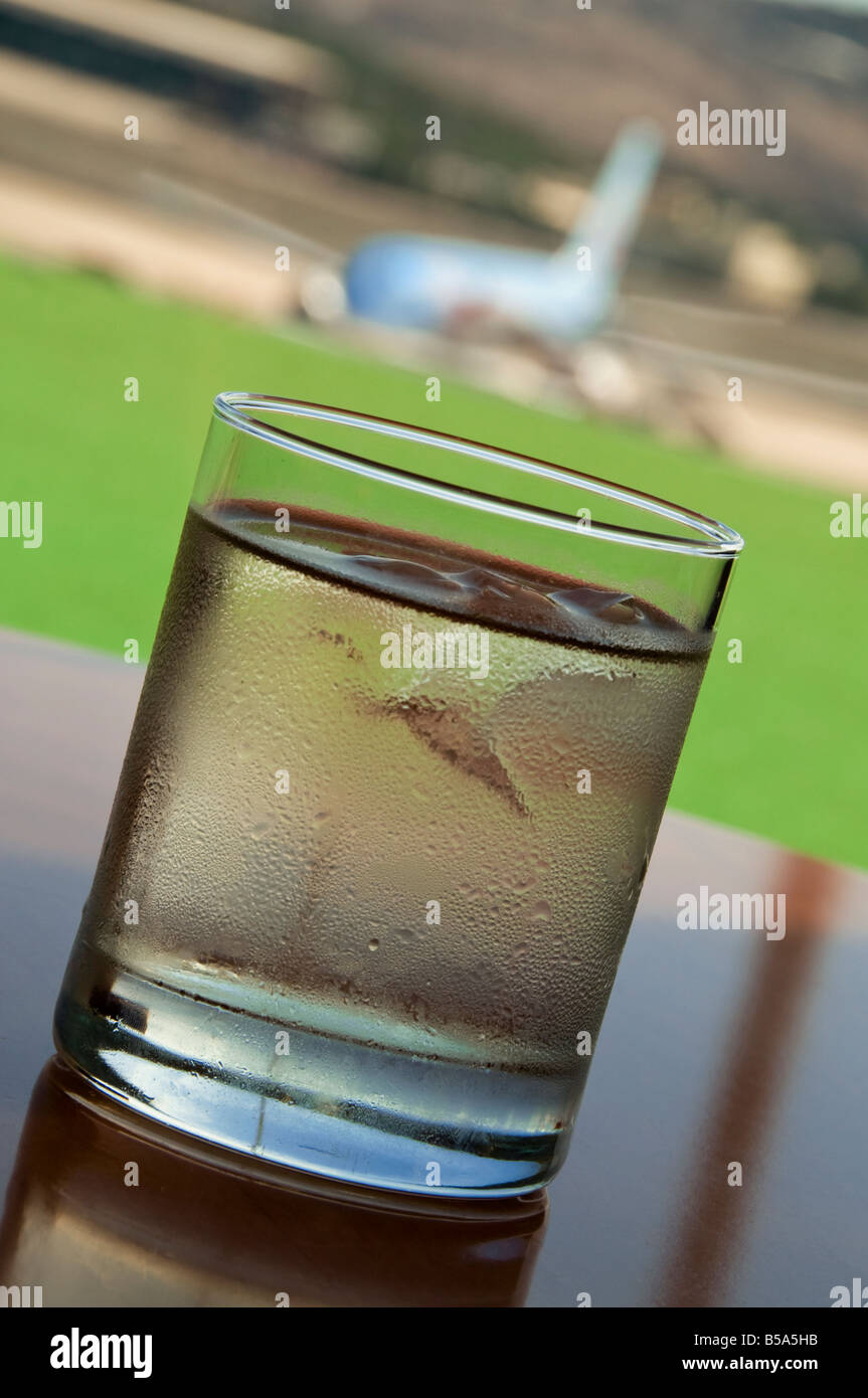 Großes Glas trockenen Martini mit Eis im Airport-Business-Lounge mit Flugzeugen auf Stand im Hintergrund Stockfoto