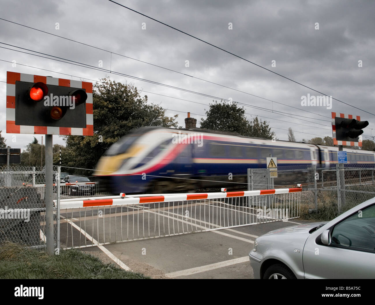 Autos warten auf eine Bahnüberfahrt für eine hohe Geschwindigkeit Zug um Zug Stockfoto