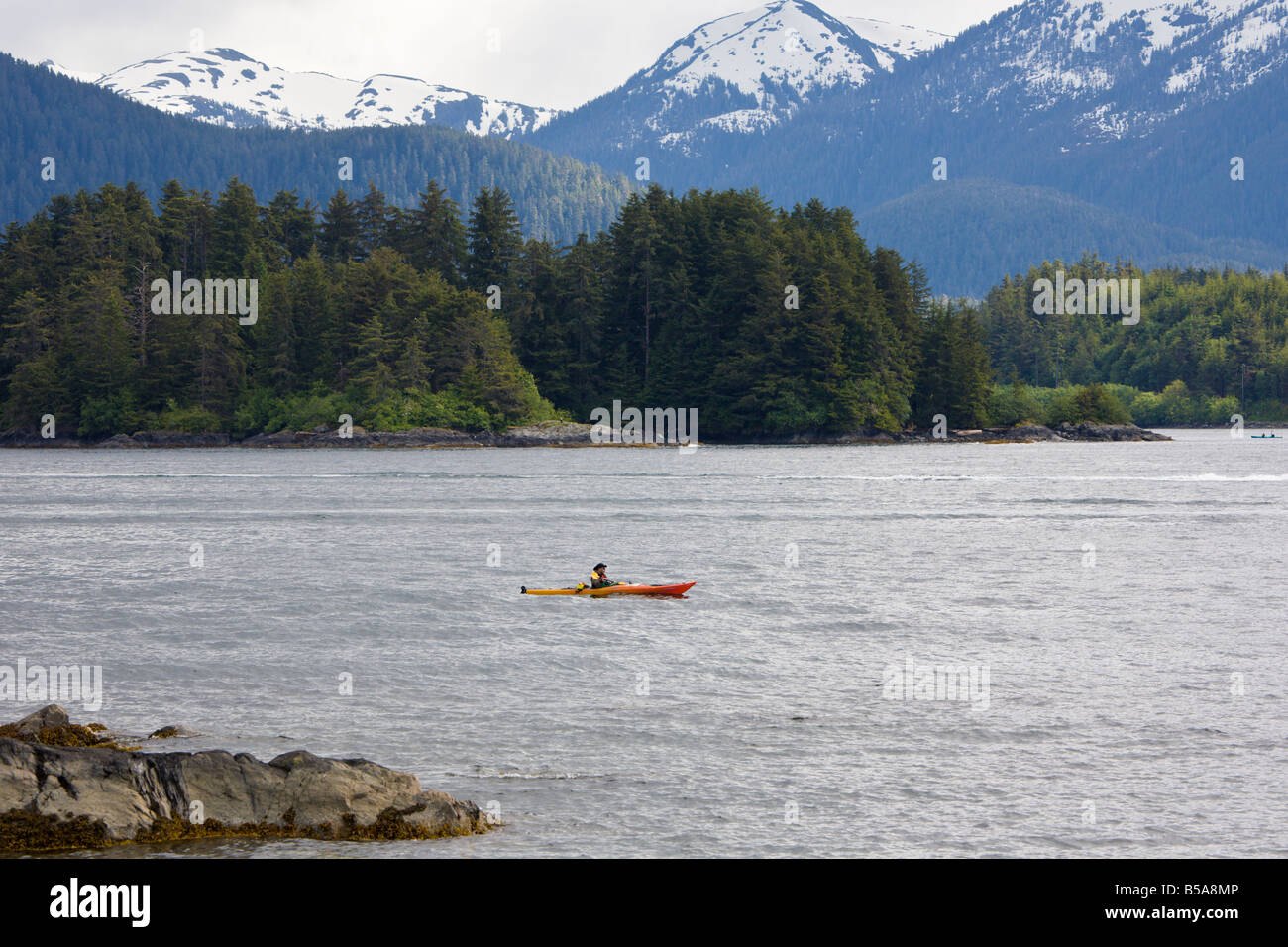 Kajakfahrer geht vor Schnee bedeckt Berge im östlichen Ärmelkanal der Inside Passage in Sitka, Alaska Stockfoto