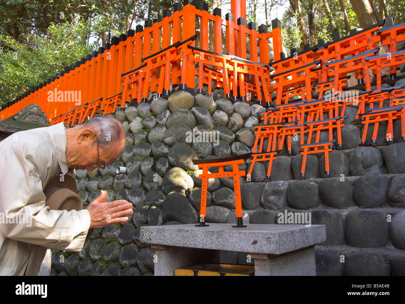 Pilger beten am Altar mit Miniatur orange Torii im Hintergrund, Fushimi