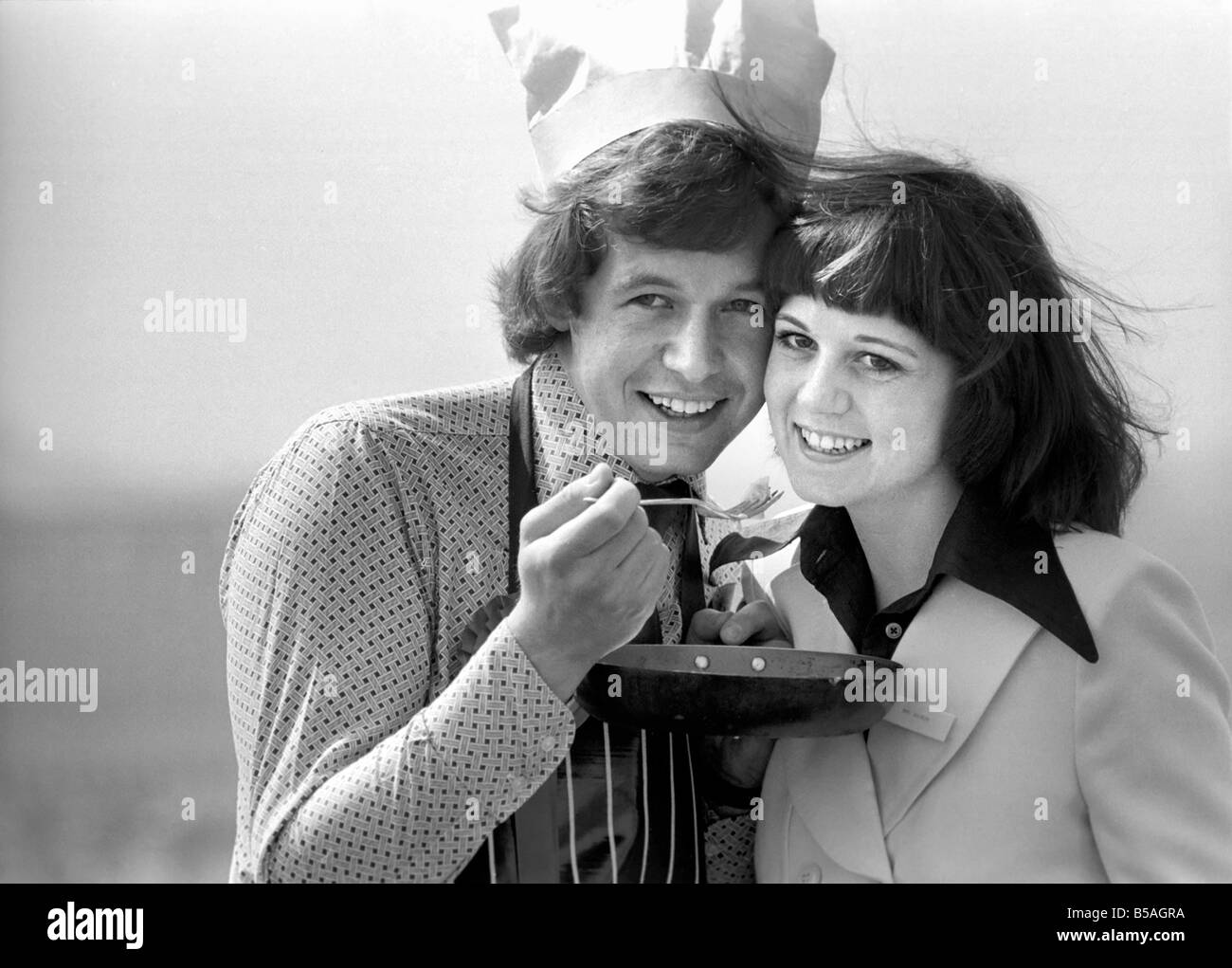 Englands Top-Mann in der Küche seine Nahrung mit einer Frau, aus der Pfanne Essen zu teilen. &#13; &#10; April 1975 &#13; &#10; 75-2138-009 Stockfoto