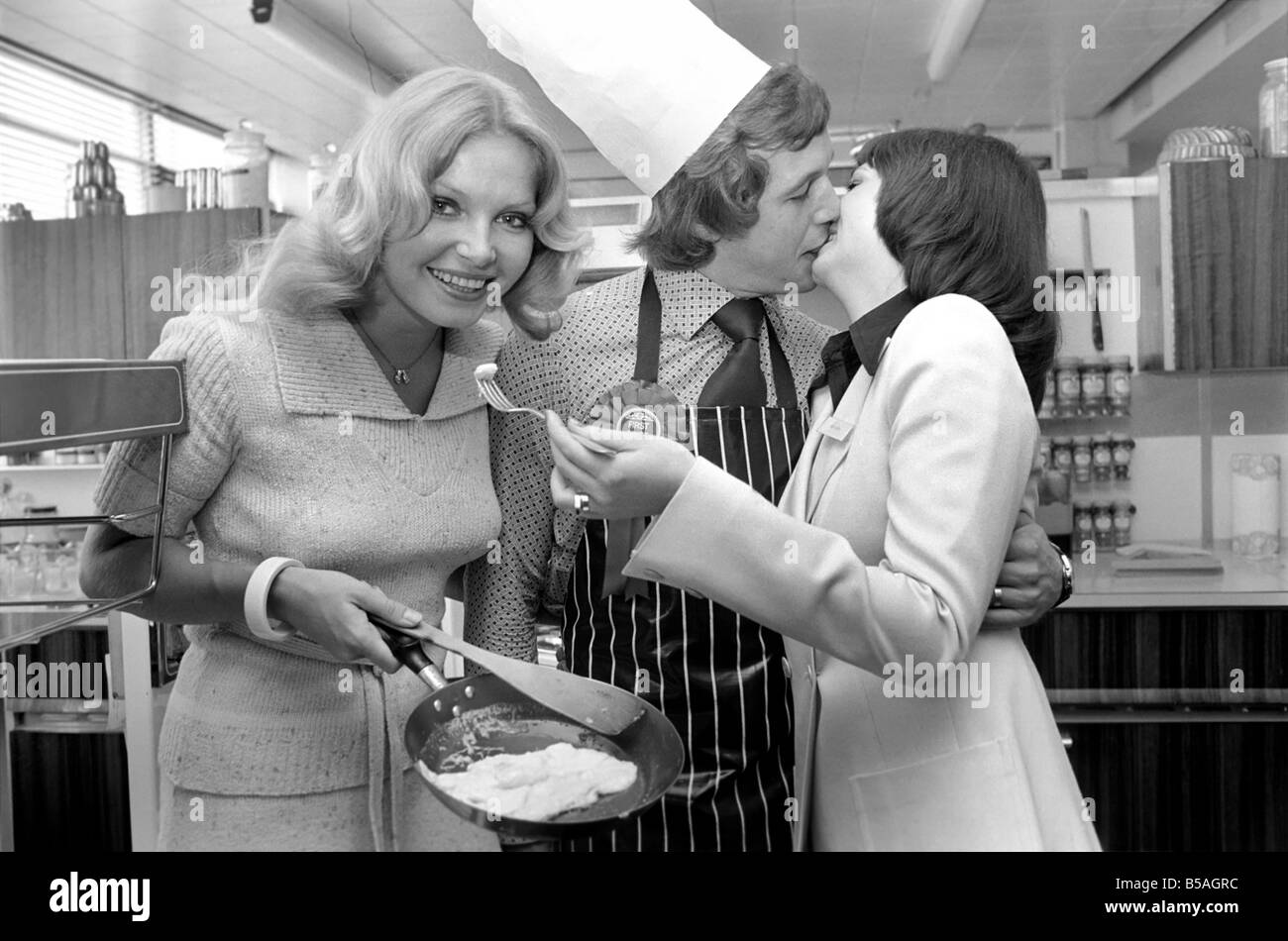 Englands Top-Mann in der Küche seine Nahrung mit einer Frau, aus der Pfanne Essen zu teilen. &#13; &#10; April 1975 &#13; &#10; 75-2138-011 Stockfoto