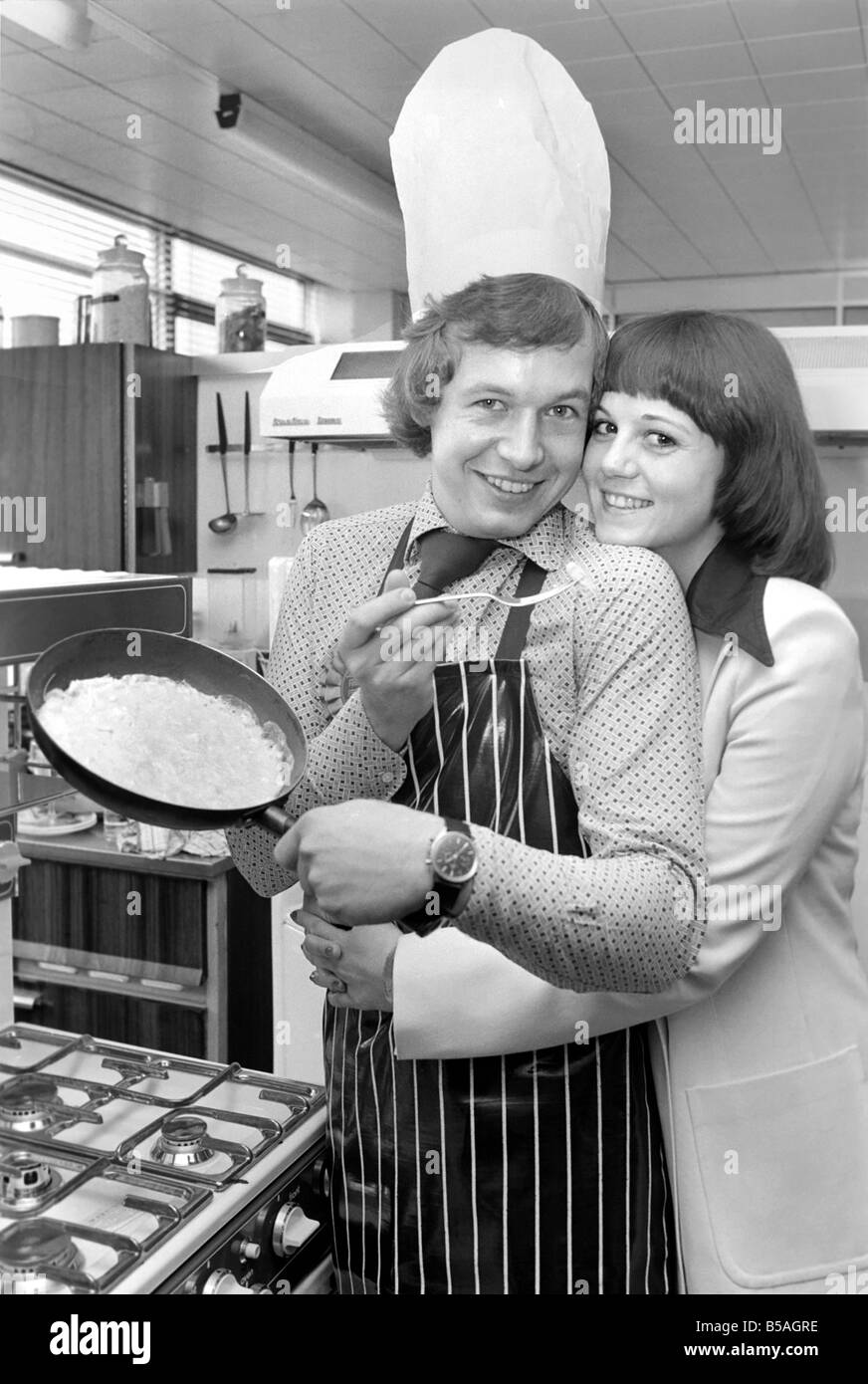 Englands Top-Mann in der Küche seine Nahrung mit einer Frau, aus der Pfanne Essen zu teilen. &#13; &#10; April 1975 &#13; &#10; 75-2138-012 Stockfoto