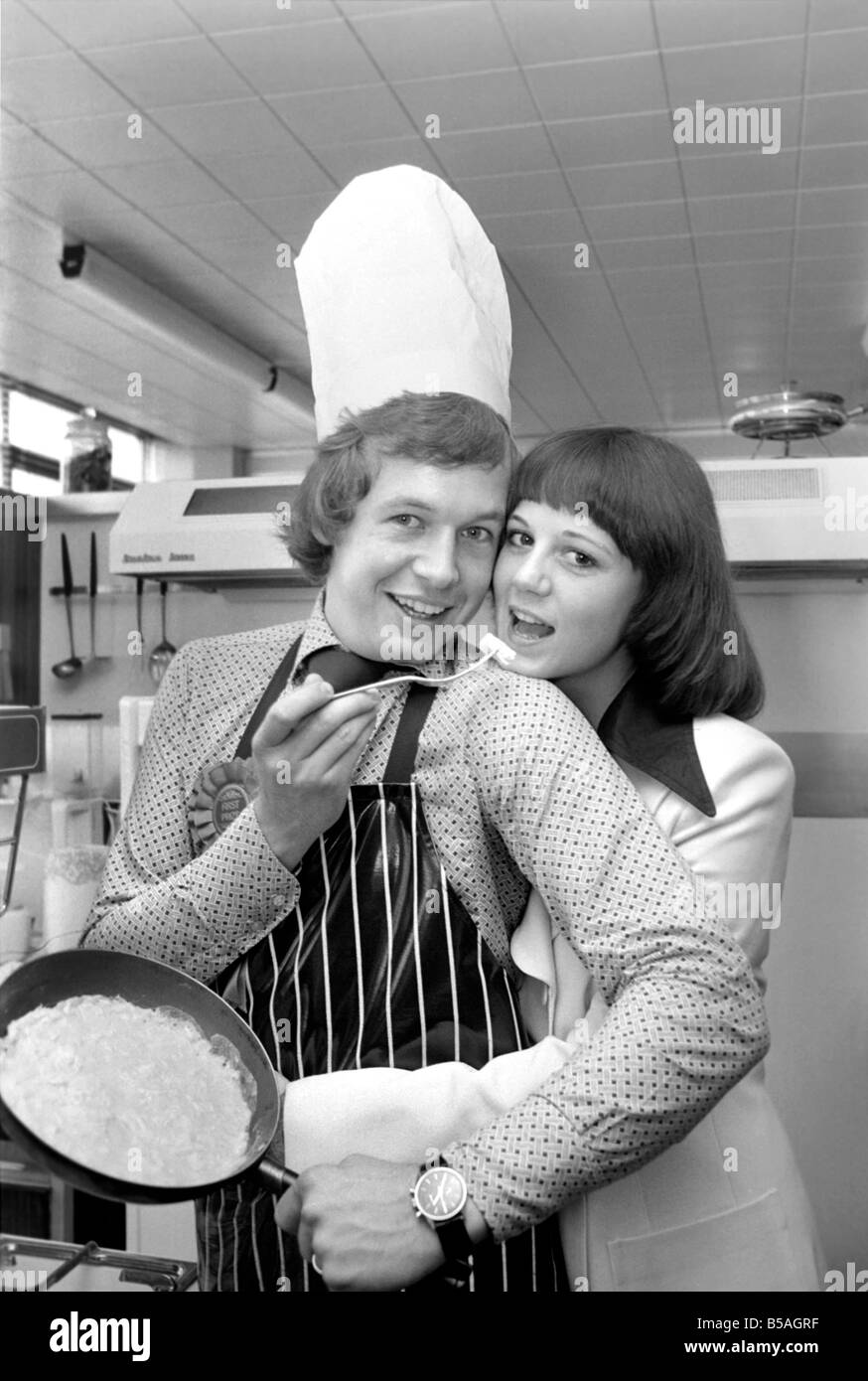 Englands Top-Mann in der Küche seine Nahrung mit einer Frau, aus der Pfanne Essen zu teilen. &#13; &#10; April 1975 &#13; &#10; 75-2138-013 Stockfoto