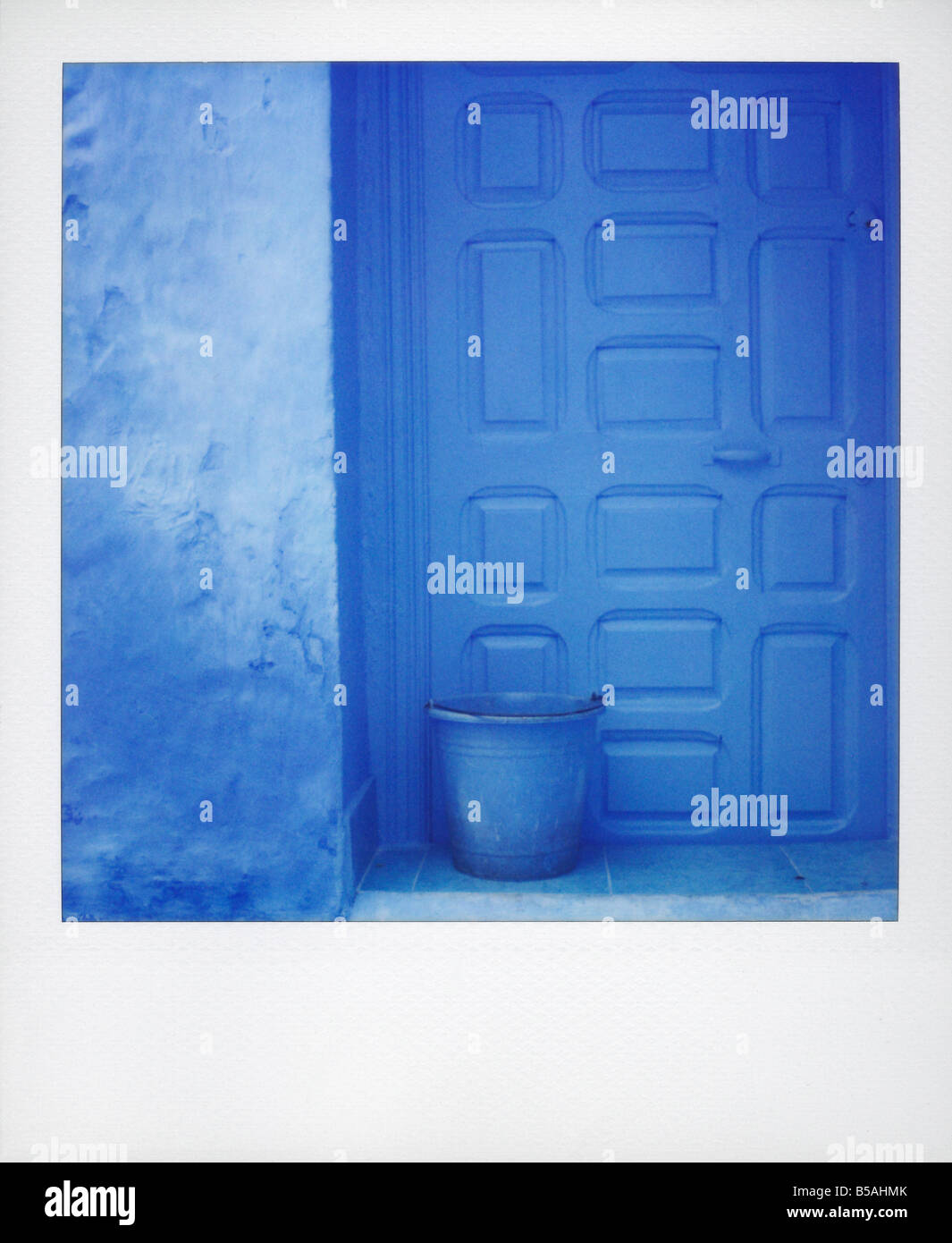 Polaroid von blauen Kunststoff-Eimer gegen blaue Tür und blaue Wand Chefchaouen Marokko Nordafrika Afrika Stockfoto