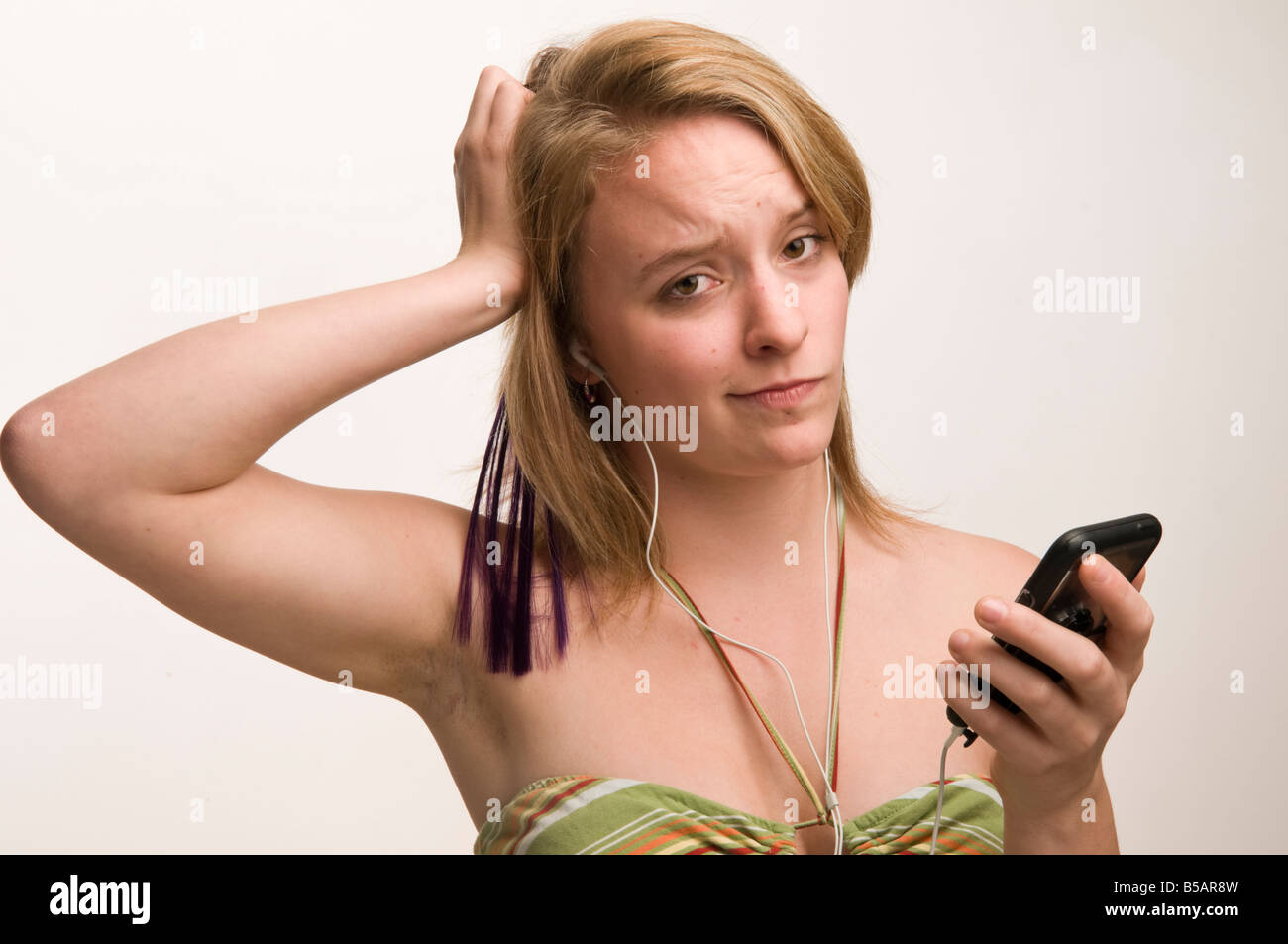 junge Frau Teenager-Mädchen anhören von Musik auf ihrem iPod Touch verwirrt durch die Technologie Stockfoto