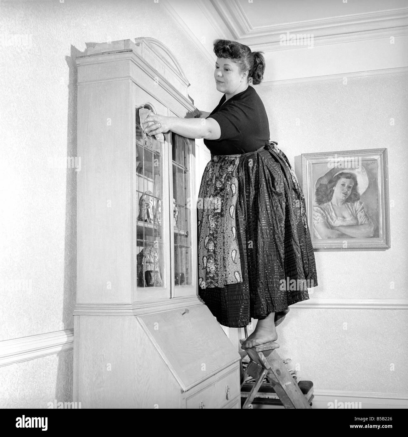 Häuslichen Lebens: Frau (Frau Olive Haugh) Abstauben Bücherregal:. Ca. 1954  Stockfotografie - Alamy
