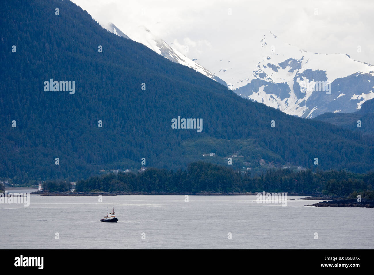 Kommerzielle Schlepper fährt die Gewässer der Inside Passage in der Nähe von Sitka Alaska vor schneebedeckten Bergen Stockfoto