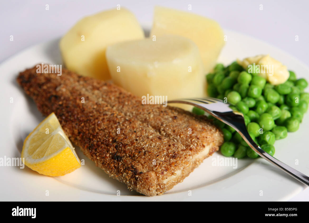 Fisch in Haferflocken, gebraten und serviert mit Salzkartoffeln und Erbsen Stockfoto