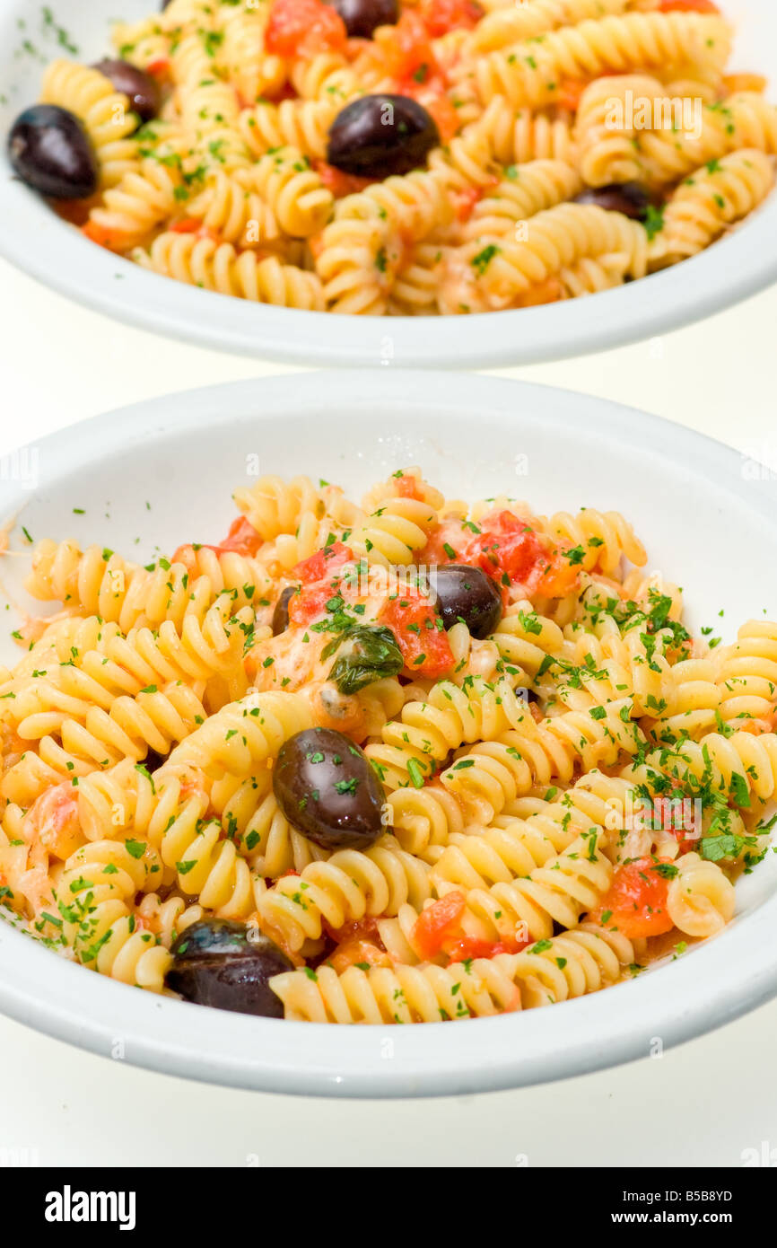 Zwei Teller von Fusilli mit Käse, frischen Tomaten und Oliven isoliert auf weiß Stockfoto