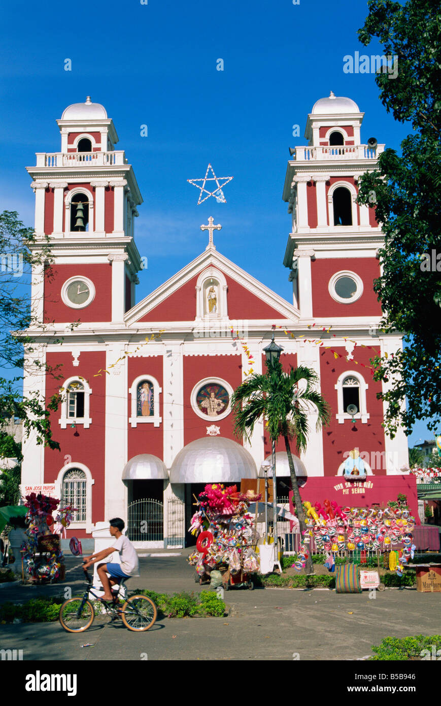 Junge auf Fahrrad und Stall zu verkaufen Spielzeug und Masken außerhalb San Jose Pfarrkirche in Iloilo City auf Panay Insel der Philippinen-A Stockfoto