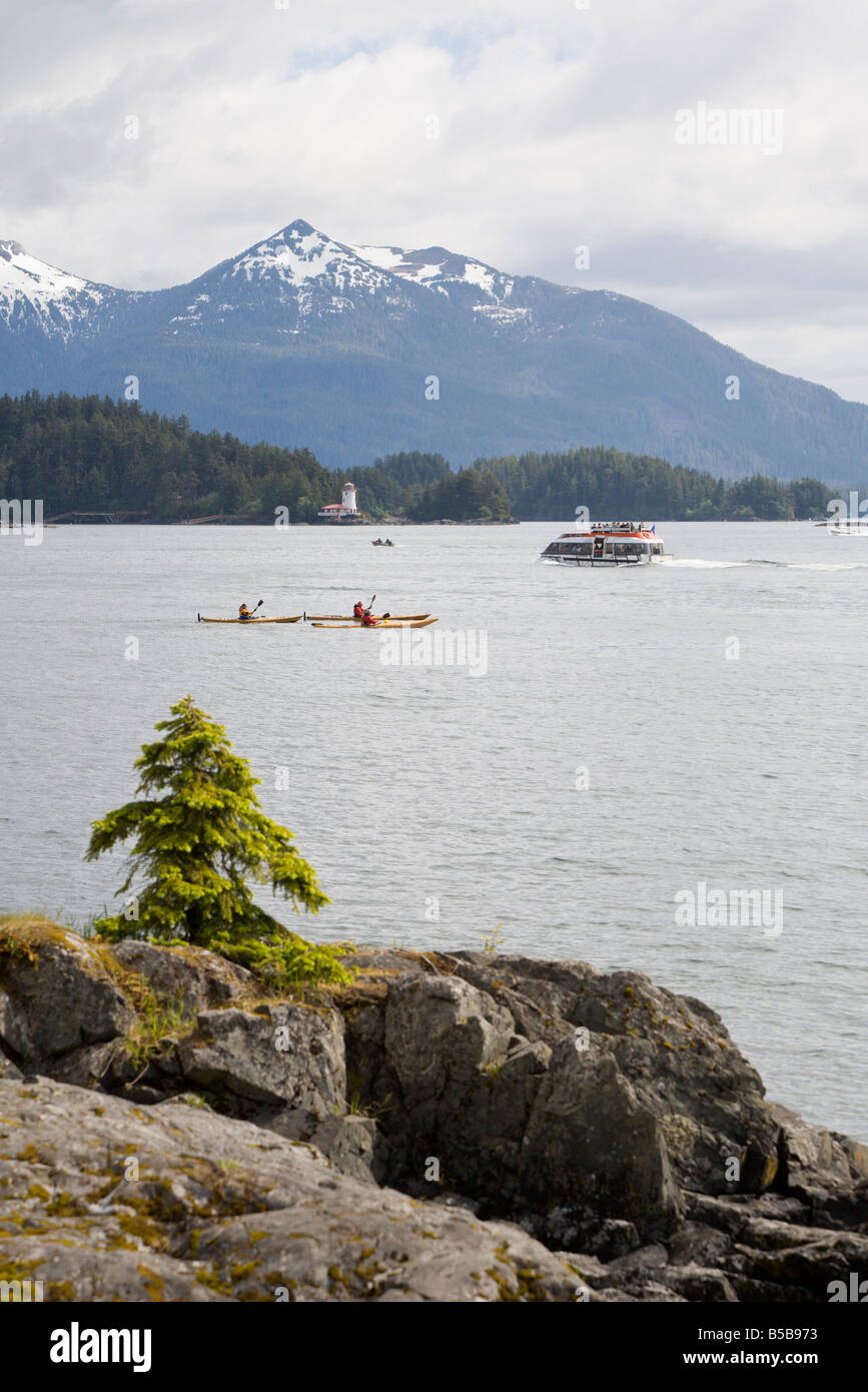 Kajakfahrer pass vor schneebedeckten Bergen und Leuchtturm im östlichen Ärmelkanal der Inside Passage in Sitka, Alaska Stockfoto