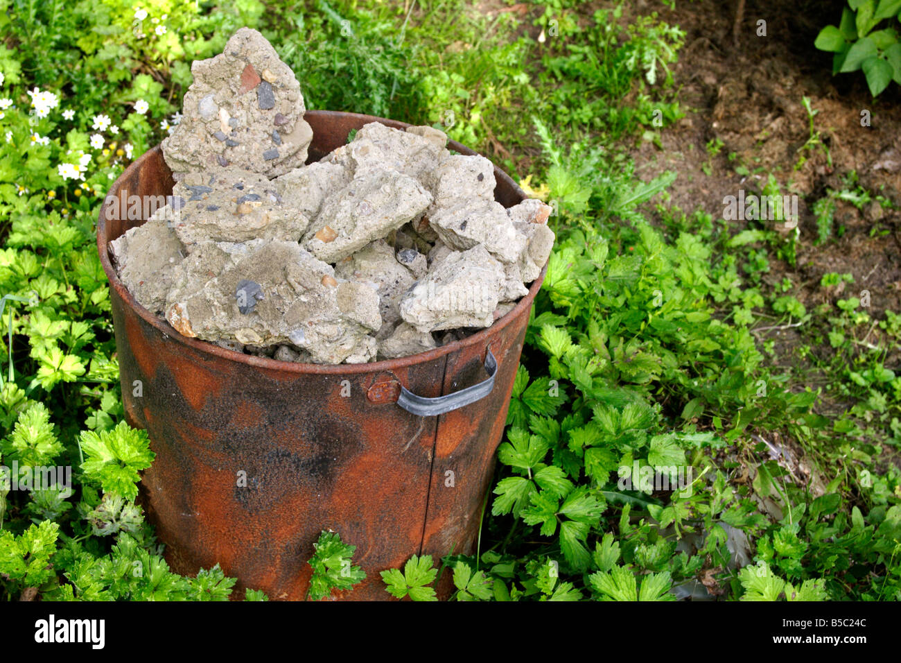 Rostige bin mit Betonschutt im Garten Stockfoto