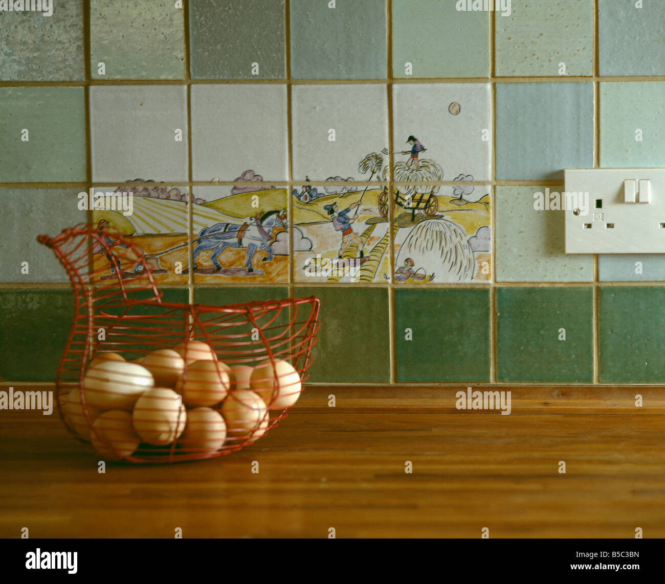 Nahaufnahme der Korb mit frischen Eiern auf Küchenarbeitsplatte mit bildhaften Fliesen und grüne Fliesen an Wand Spritzschutz Stockfoto