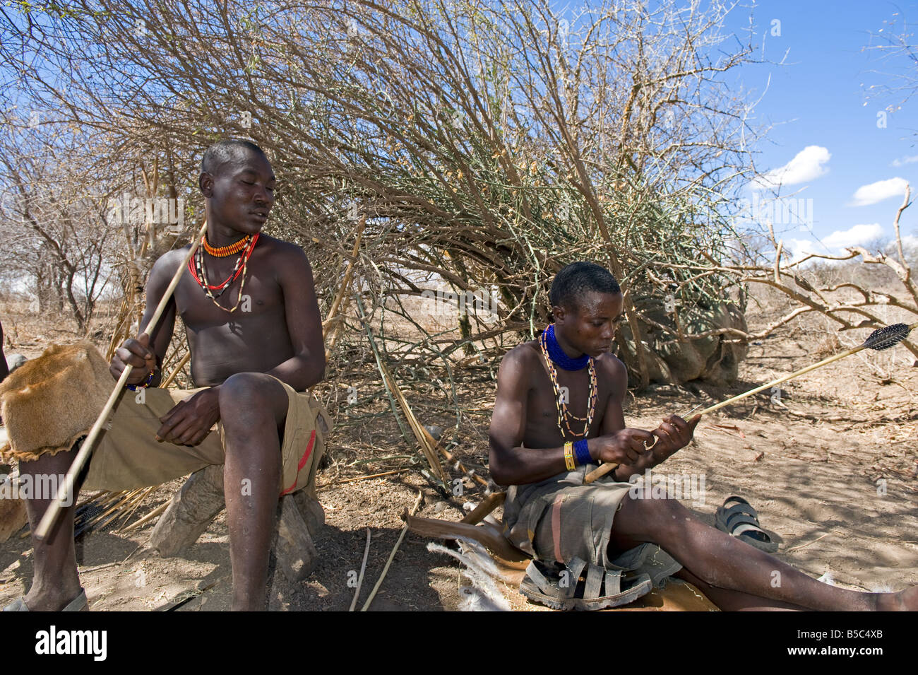 Mitglieder des Stammes Hadza untersuchen einen Pfeil vor dem Schlafengehen, Lake Eyasi Tansania zu jagen Stockfoto