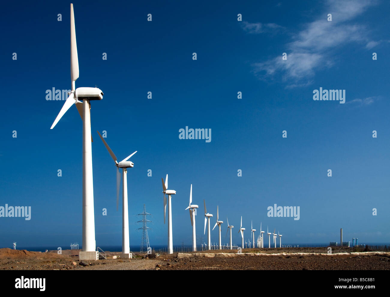 Windkraftanlagen mit Strommasten und Kraftwerk an der Küste in Kanarische Inseln-Spanien Stockfoto