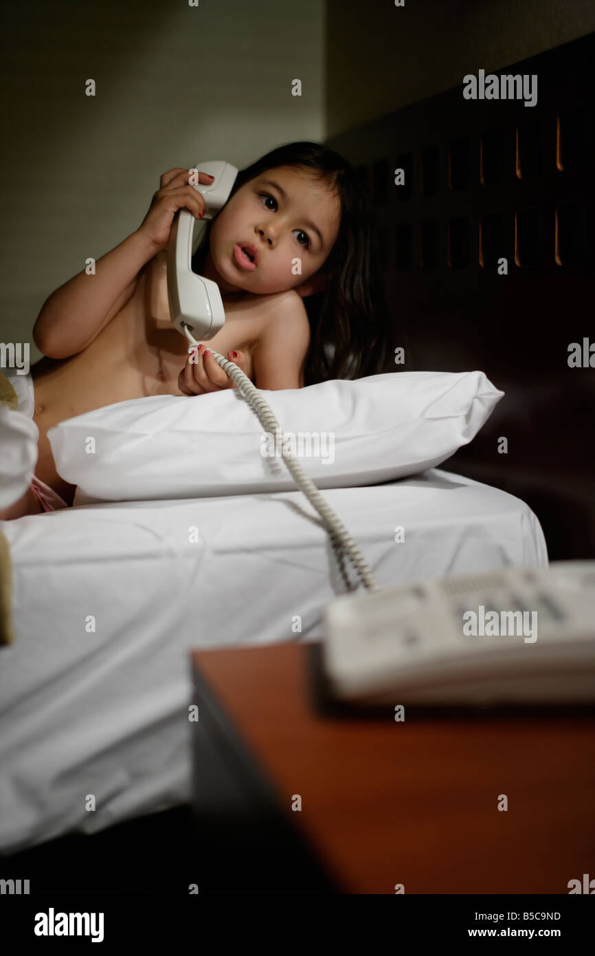 Mädchen im Bett mit Telefon sechs 6 Jahre alt Stockfoto