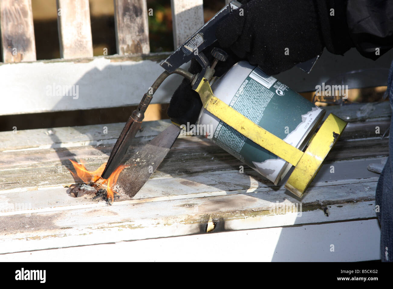 Unter Verwendung eines Gas-Lötlampe und Schaber, um alten Farbe von einem Garten-Sitzplatz vor dem Neuanstrich zu verbrennen. Stockfoto