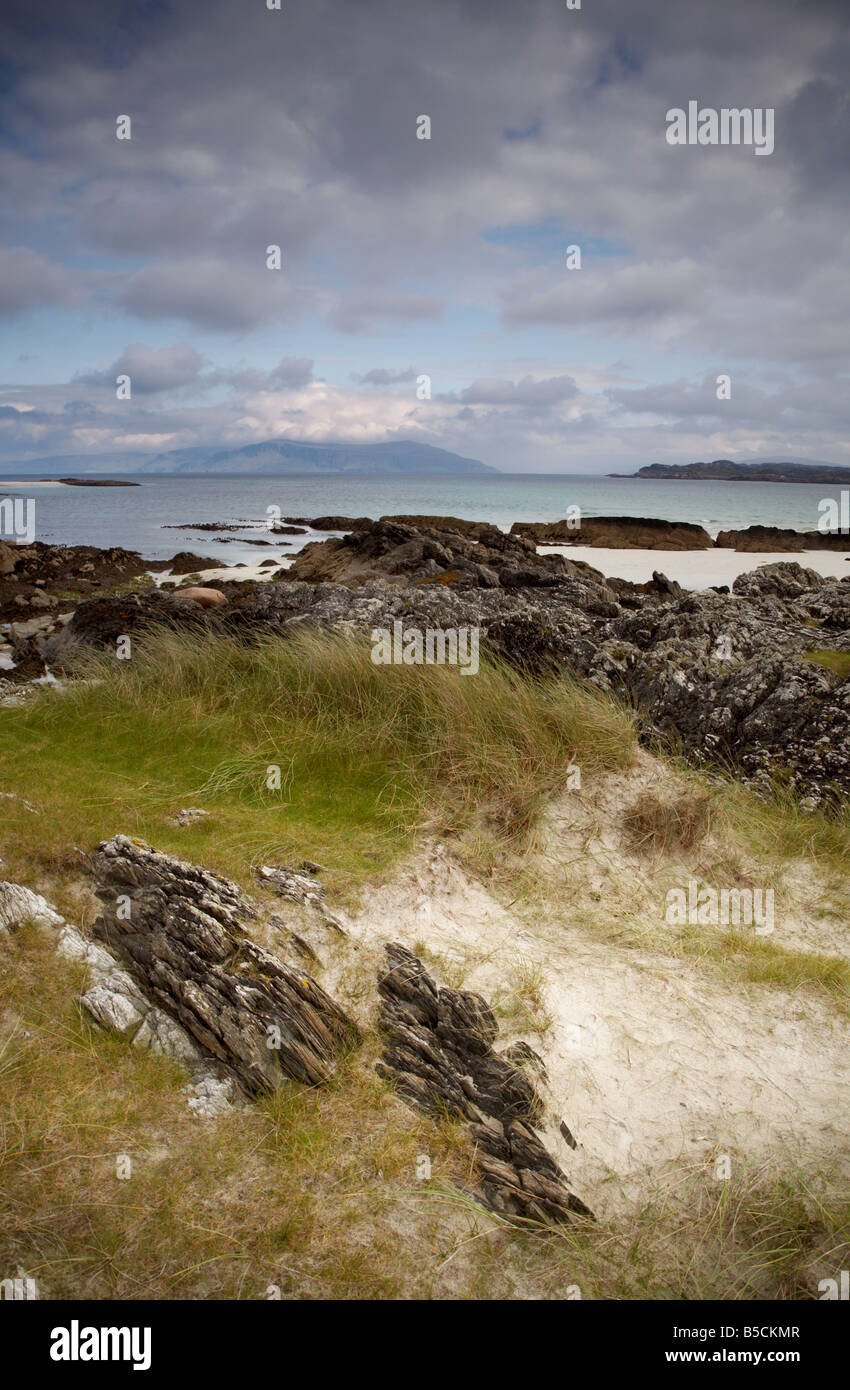 Rock-Rasen und Sand am North Shore Beach der Insel Iona in Schottland mit der Isle of Mull am Horizont Stockfoto