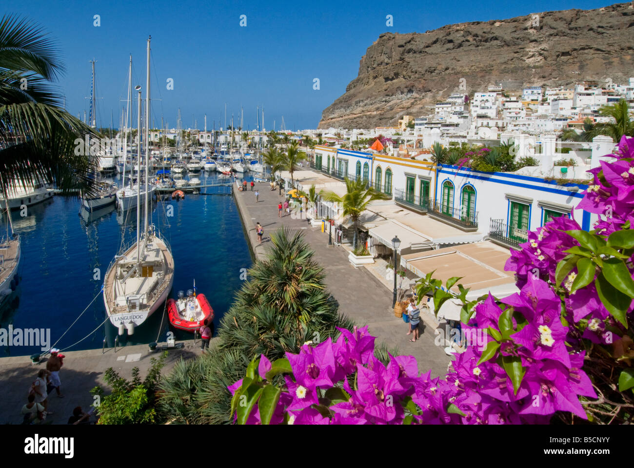 Puerto de Mogan übersicht Geschäfte restaurants bars gesehen über Bougainvillea Blumen, Yachthafen und Promenade. Gran Canaria Kanarische Inseln Spanien Stockfoto