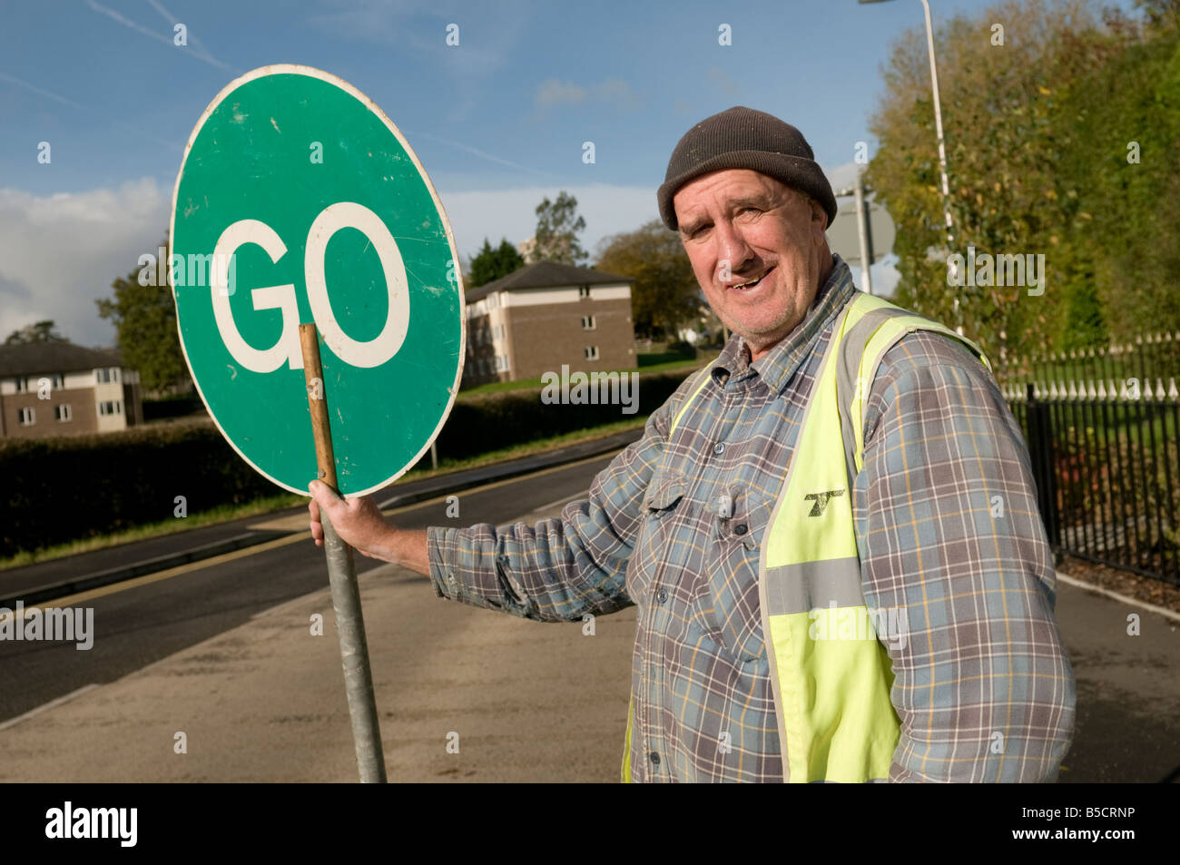 Mann controlling Verkehr mit einer Hand gehalten rotierenden Stop gehen am Pol bei Straßenbauarbeiten unterzeichnen Stockfoto