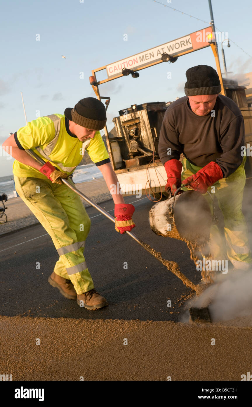 Zwei Männer mit hoher Reibung anti-rutschfeste Straße Oberfläche "Vorsicht Männer zur Arbeit", Aberystwyth Wales UK Stockfoto