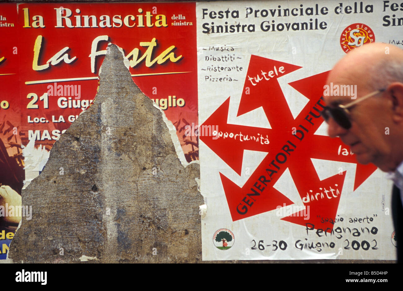 Vorbei an Interesse. Ein Mann zu Fuß vorbei an ein paar alten fliegen-Plakaten, zeigt kein Interesse an ihnen. Fotografiert in Pisa, Italien. Stockfoto
