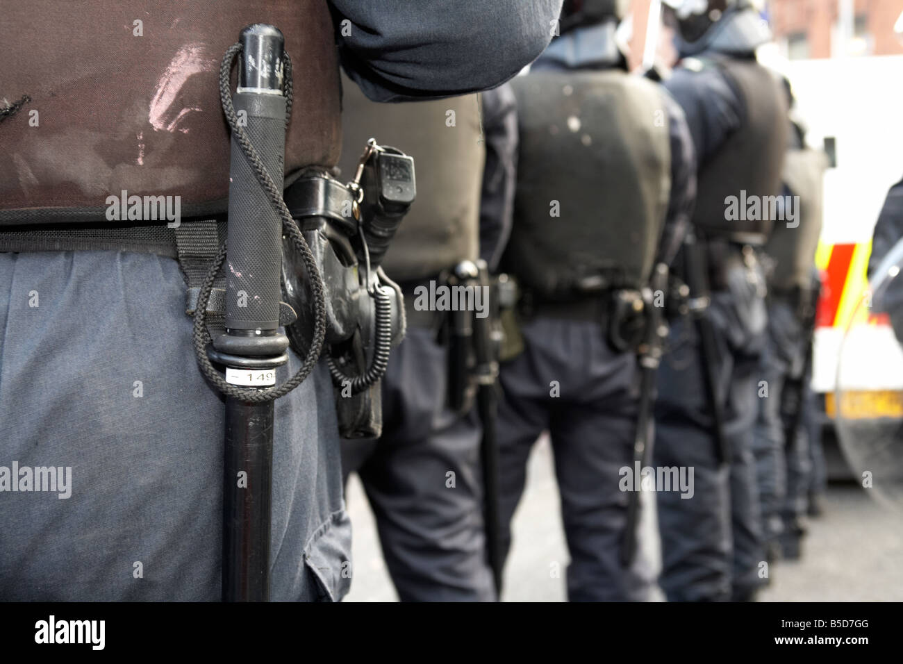 Reihe von PSNI Police Service of Northern Ireland Riot Squad Offiziere tragen Schlagstöcken Handfeuerwaffen und Kampfausrüstung Stockfoto