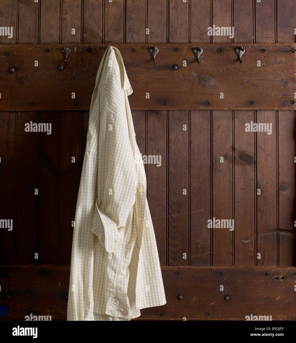 Arbeitshemd an Haken hängen verwitterte Holz Wand Stockfoto