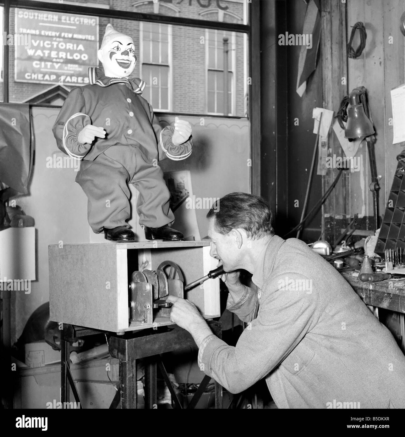 Die Werkstatt von einer Midlands Plastikfigur Fabrik, die eine Vielzahl von Produkten aus Puppen verwendet im Messegelände Vergnügungen zu Shop Schaufensterpuppen herstellen. Unser Bild zeigt einen Mechaniker überprüfen die Maschinerie der ein Lachen Clown Jahrmarktsattraktion. Januar 1954 Stockfoto