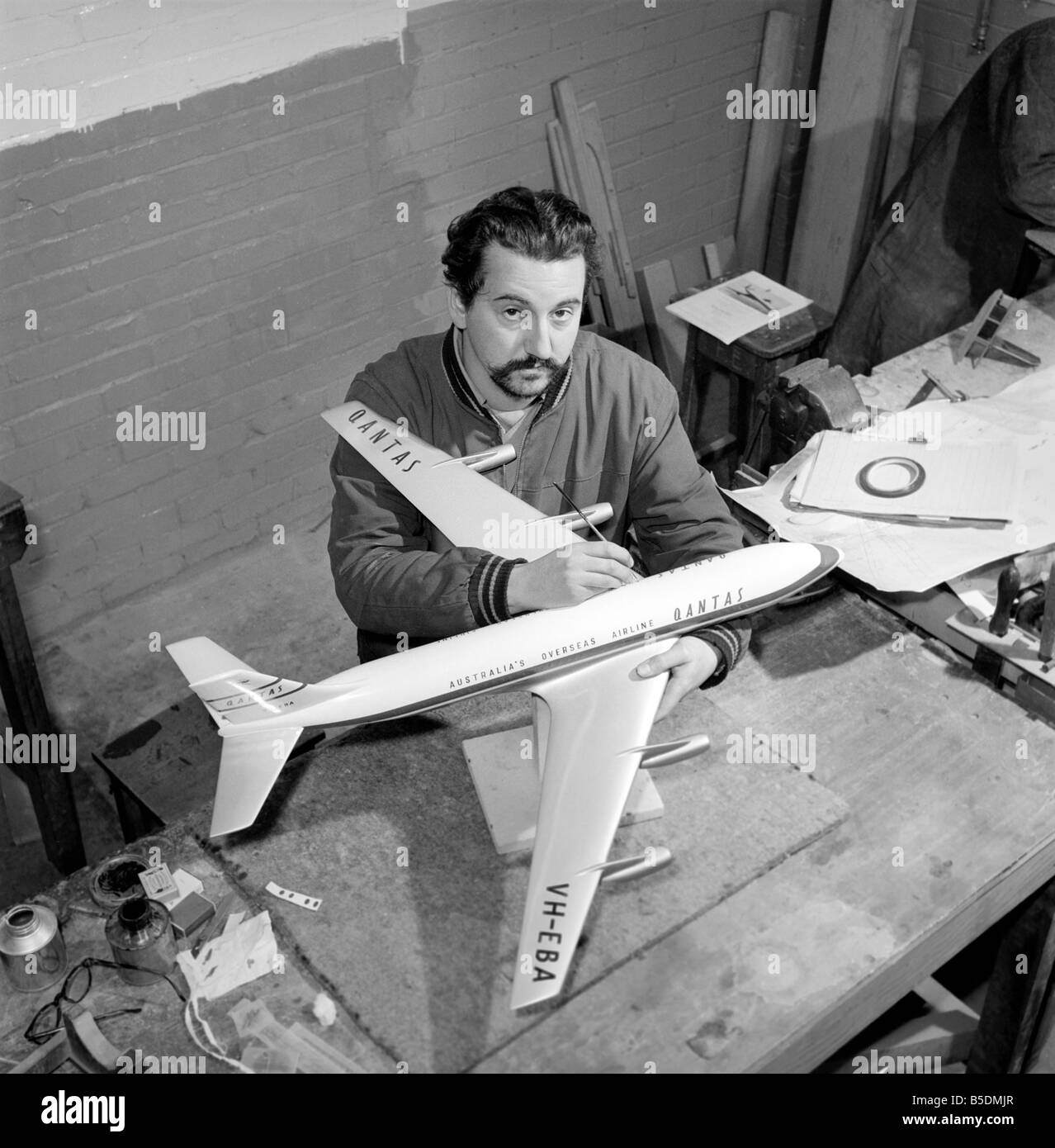 Fabrik wo Flugmodelle für die Reisebüros vorgenommen werden. Männer machen Modellflugzeuge. Modell Hersteller Malerei Rumpf des Modells ca. 1960 Stockfoto