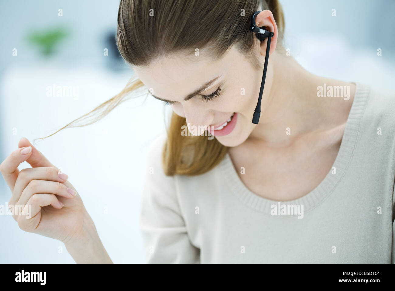 Junge Frau trägt Kopfhörer, spielen mit Haaren und blickte lächelnd Stockfoto
