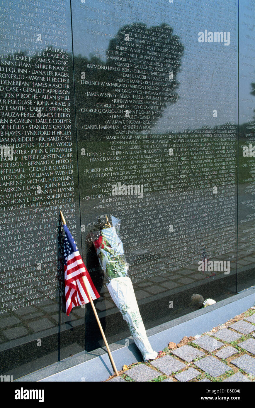 Flagge und Blumen gegen die Liste der Namen auf den Vietnam Veterans Memorial in Washington DC USA J Hodson Stockfoto