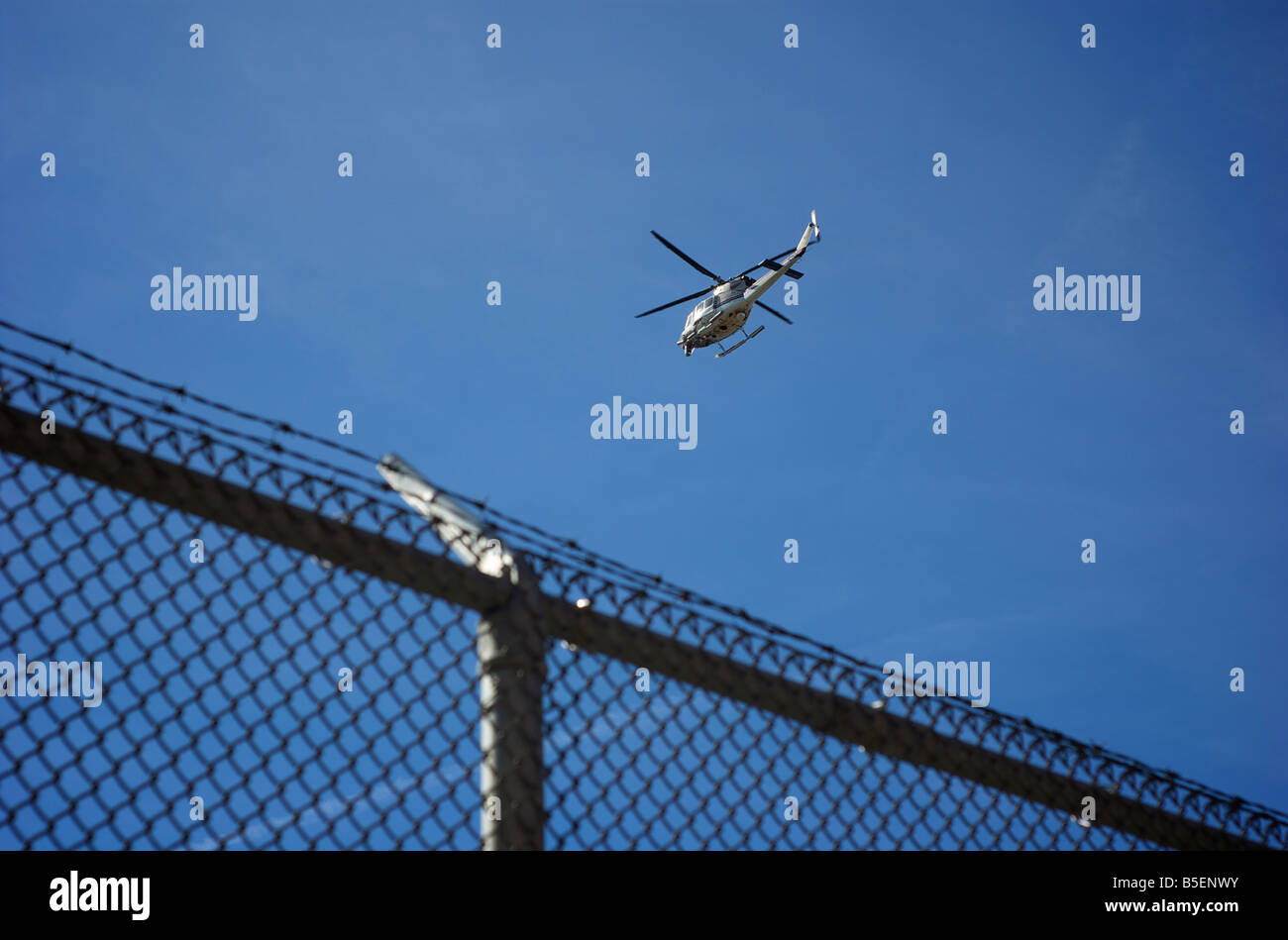 Hubschrauber fliegen über dem Stacheldrahtzaun Stockfoto