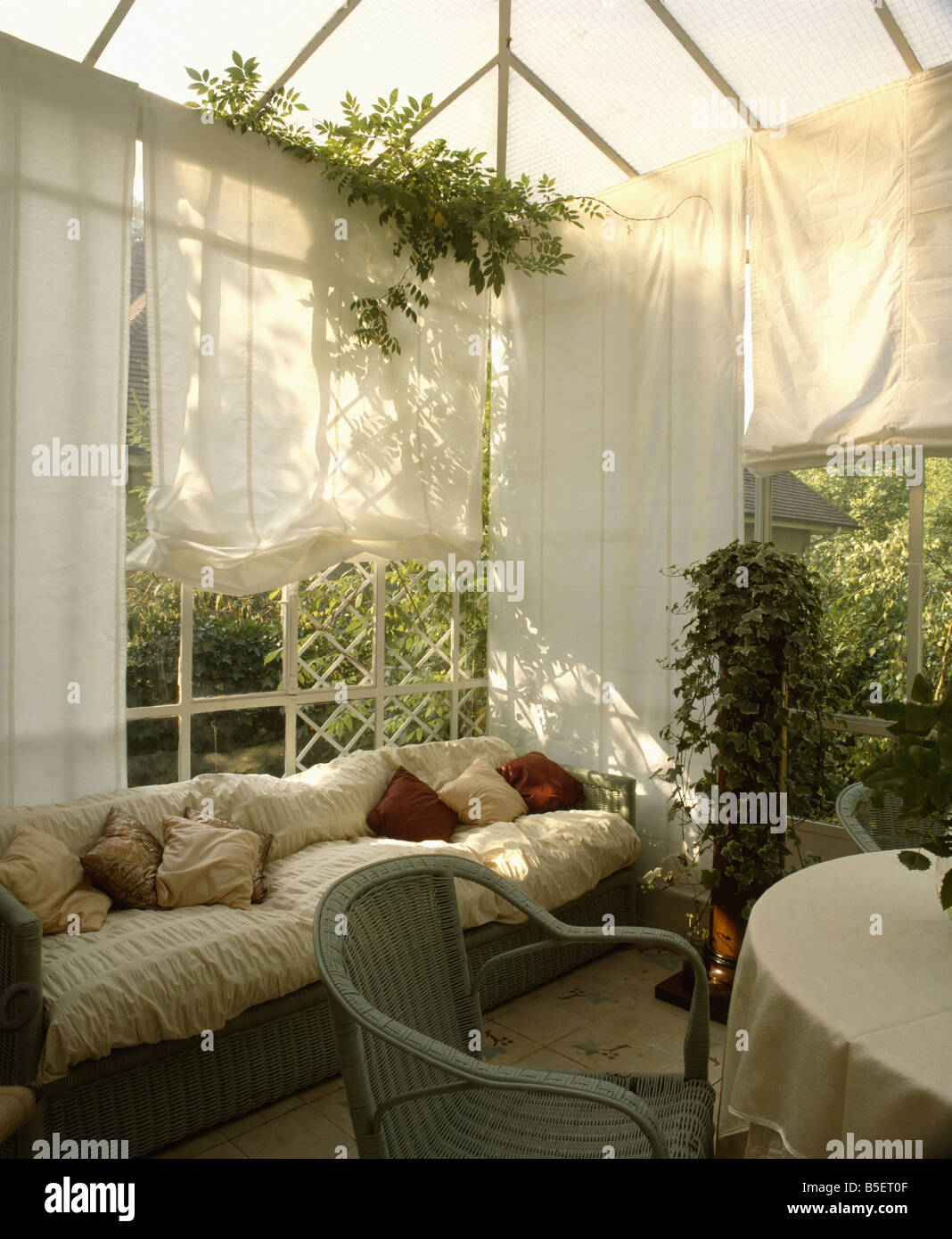 Creme auf Sofa im Wintergarten mit Creme Baumwolle Vorhänge an den Fenstern  werfen Stockfotografie - Alamy