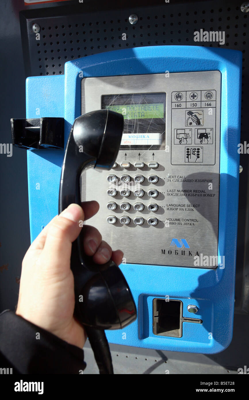 Eine Hand auf einen Telefonhörer von einer öffentlichen Telefonzelle Stockfoto