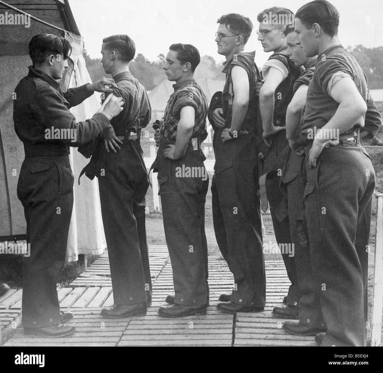 Neue Armee Rekruten warten im Einklang mit ihren Ärmel aufgerollt, während sie darauf warten, die geimpft werden, bevor sein Übersee abgeschickt, kämpfen im zweiten Weltkrieg; Oktober 1939 Stockfoto