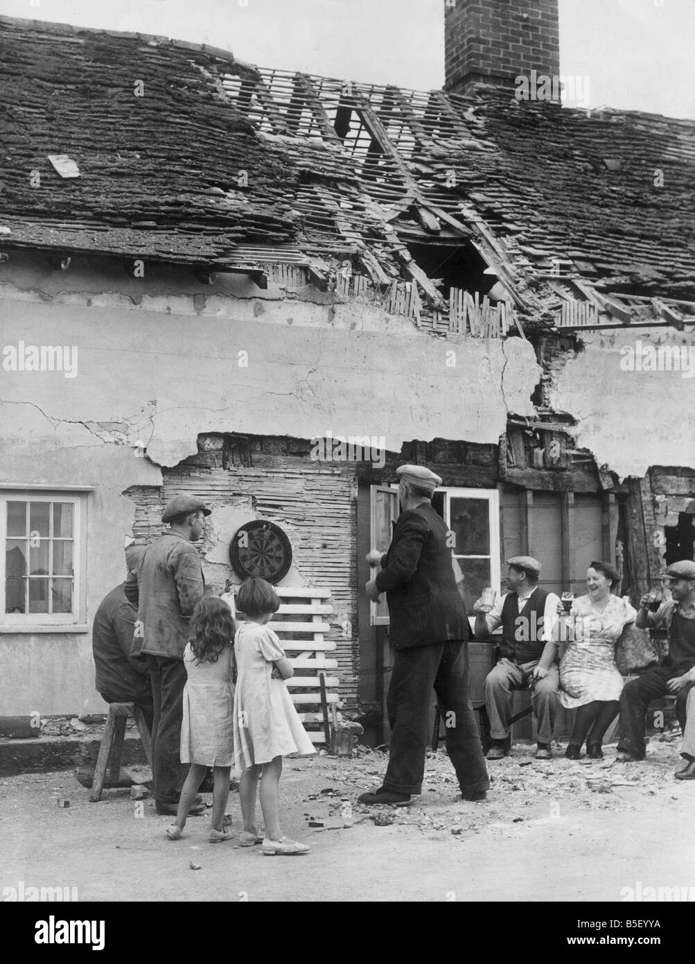 Leben führt wie gewohnt in einem Land Pub in England. Einheimischen genießen ein kühles Bier und eine Runde Darts auf eine Bombe beschädigt pub Stockfoto